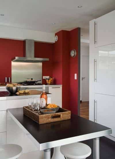 Cocina pared roja con muebles blancos