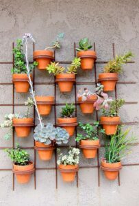 maceta de suculentas colgadas en muro de jardin